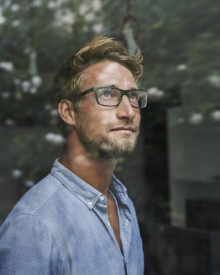 Junger Mann mit Brille schaut aus dem Fenster